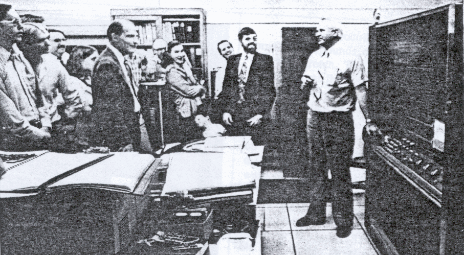 STRETCH OUT: Bill Ivie tried to get others to pull the switch on Stretch for the final time at BYU's September 1980 shutdown of the system To the left with coat and tie is computer services manager Willard Gardner, and the bearded gentleman in the center is Joe Wise, who first found the Stretch listed in a government surplus inventory and campaigned for its acquisition. 
