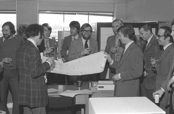 FR80 output of the acceptance tests. From L to R: Richard Hilken (Operations Manager for the two systems), Cliff Pavelin and David Thornley (Prime UK) with output, Dale Sutcliffe (graphics software), Rob Witty (Software Tools), Len Ford (Systems Programmer), Rex Blagg (Prime), Bob Hopgood (Manager) and Eric Thomas (graphics and other applications).