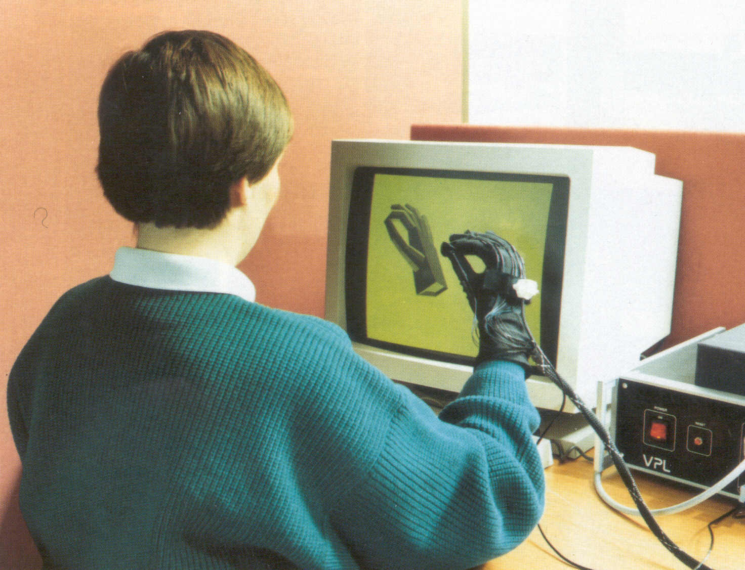 Fig 2.3 The DataGlove in use, showing the detectors, data collection system and the resulting 
image drawn on screen. As the hand and fingers move the image changes. (90RC7048)
